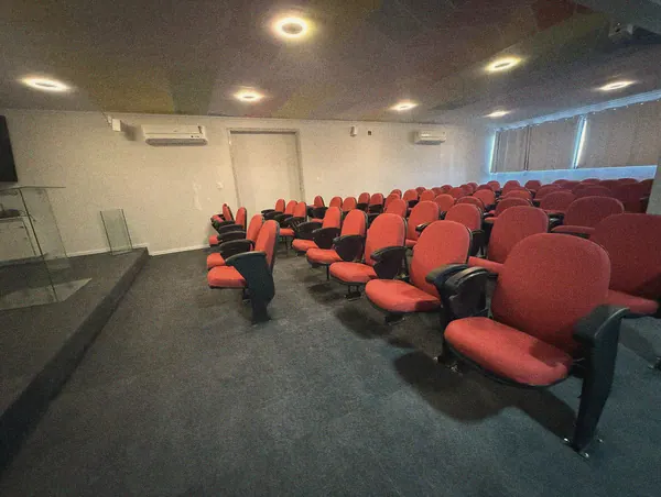 Vista do auditório a partir das poltronas, com tela e púlpito